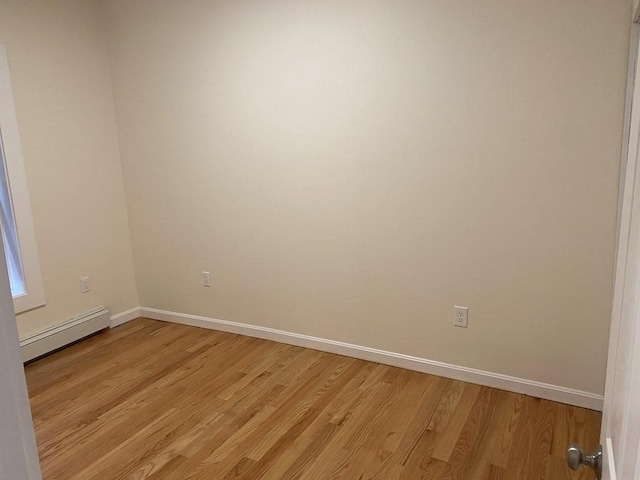 unfurnished room featuring light wood-type flooring and baseboard heating