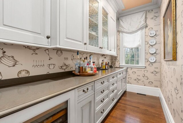 bar with white cabinetry, crown molding, and dark wood-type flooring