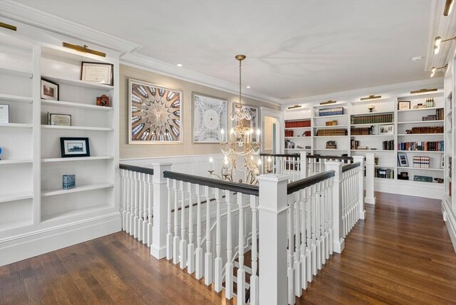 hall featuring dark wood-type flooring, crown molding, built in shelves, and a notable chandelier