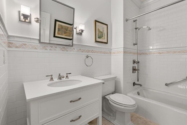 full bathroom featuring tiled shower / bath, vanity, toilet, and tile walls