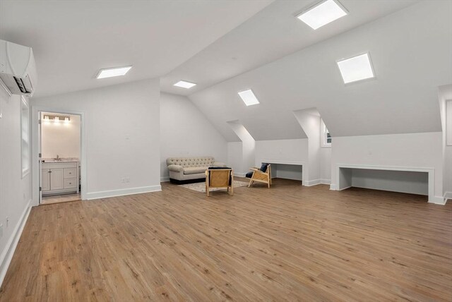 bonus room with an AC wall unit, lofted ceiling, and light hardwood / wood-style flooring