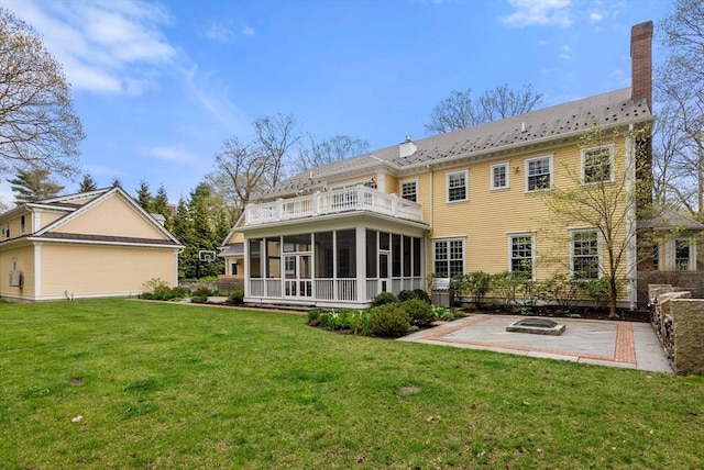 back of house featuring a patio, a sunroom, a lawn, and an outdoor fire pit