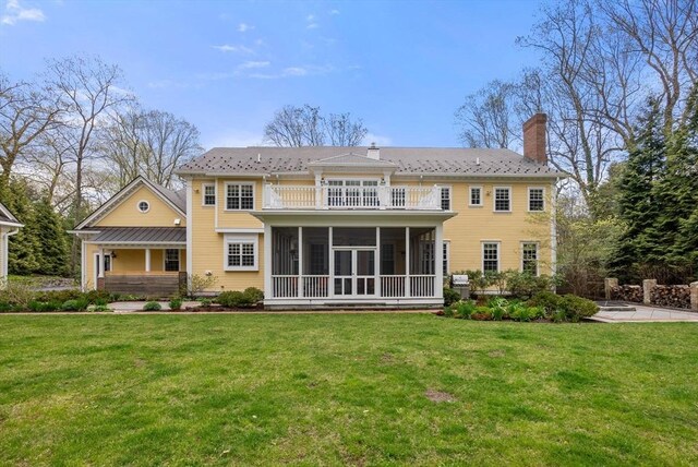 rear view of house featuring a sunroom and a yard