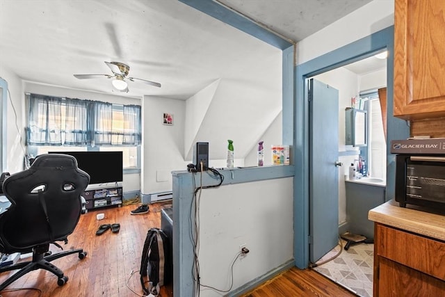 office area featuring ceiling fan, wood-type flooring, and a baseboard heating unit