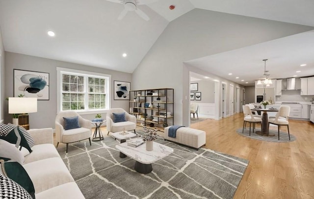 living room with light wood-type flooring, ceiling fan, and vaulted ceiling