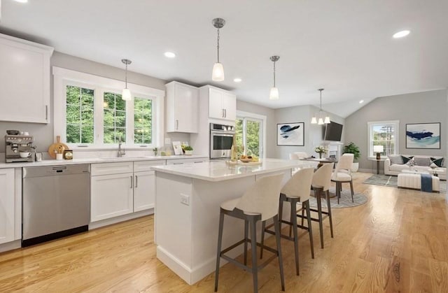 kitchen with sink, a kitchen island, white cabinetry, and appliances with stainless steel finishes