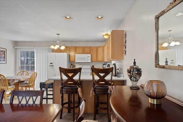 kitchen with pendant lighting, light brown cabinetry, white appliances, and a chandelier