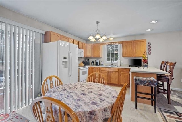 kitchen featuring sink, white appliances, an inviting chandelier, light brown cabinetry, and decorative light fixtures