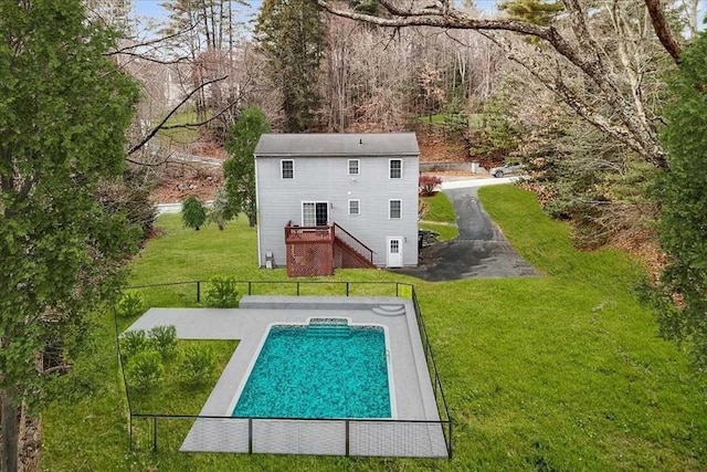 rear view of property featuring a yard and a swimming pool side deck