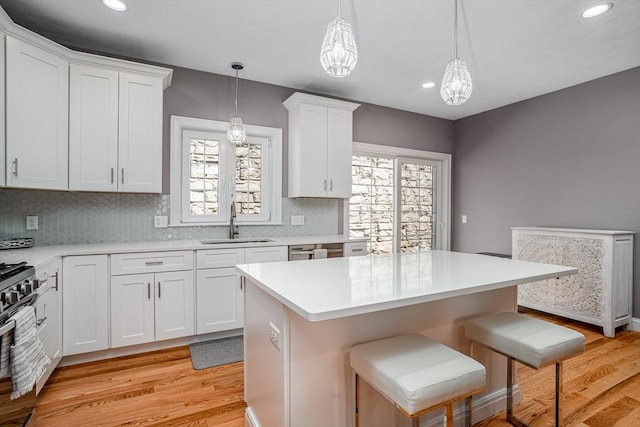 kitchen featuring light wood-type flooring, a sink, gas range, healthy amount of natural light, and recessed lighting