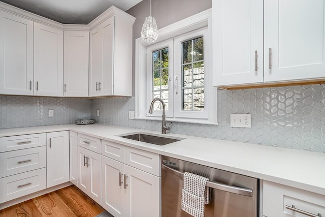 kitchen with a sink, stainless steel dishwasher, light countertops, and white cabinets