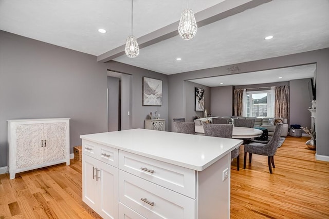 kitchen featuring light wood finished floors, white cabinets, open floor plan, light countertops, and a center island