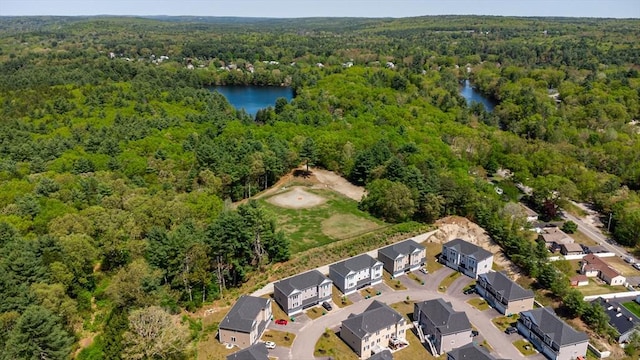 aerial view of property and surrounding area featuring a heavily wooded area, a large body of water, and nearby suburban area