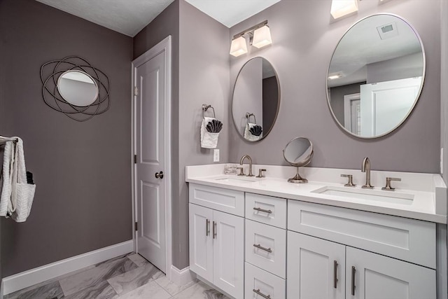 bathroom featuring marble finish floors, double vanity, and baseboards