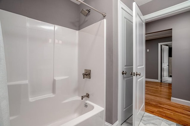 bathroom with shower / bathtub combination, baseboards, and wood finished floors