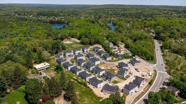 aerial view of property's location featuring a heavily wooded area, a large body of water, and nearby suburban area