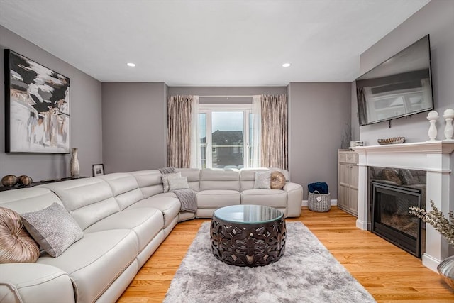 living room with recessed lighting, light wood-style flooring, and a fireplace