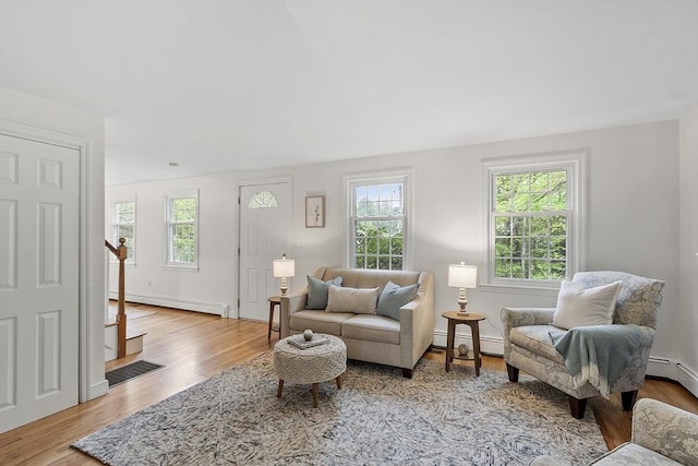 living room with a baseboard heating unit, baseboard heating, wood finished floors, and baseboards