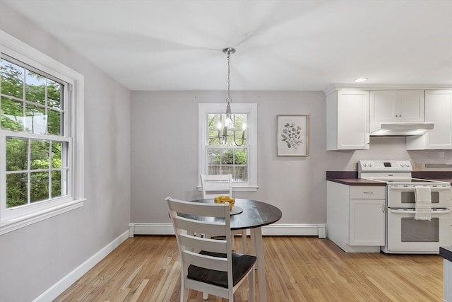 kitchen with under cabinet range hood, double oven range, healthy amount of natural light, and a baseboard radiator