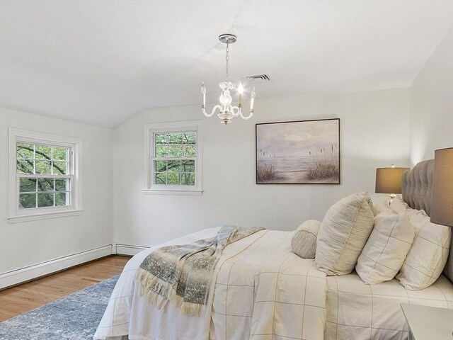 bedroom with wood finished floors, a chandelier, multiple windows, lofted ceiling, and baseboards