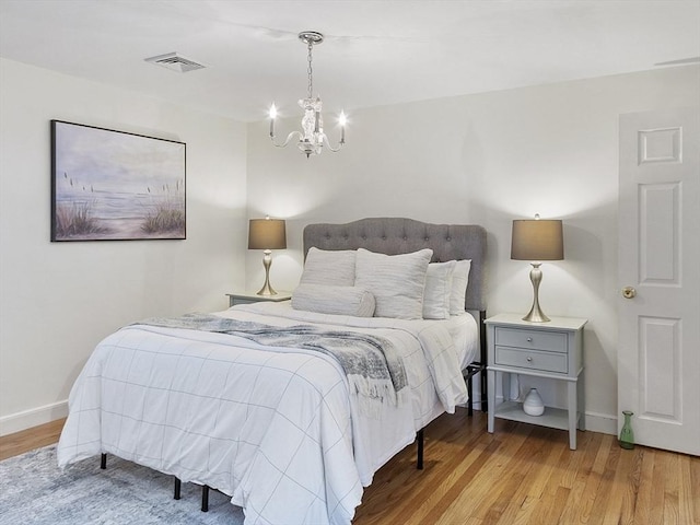 bedroom featuring a chandelier, wood finished floors, and baseboards