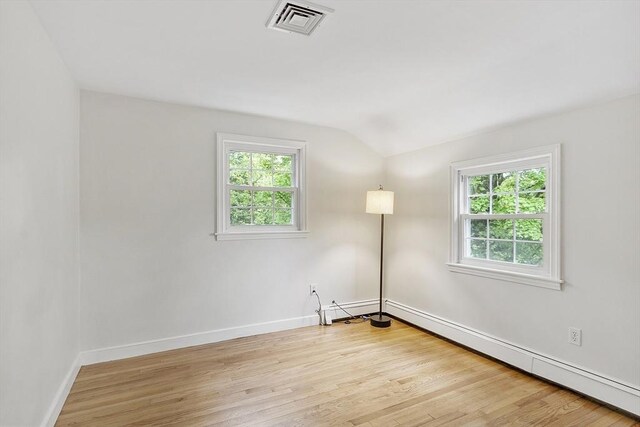 empty room featuring vaulted ceiling, healthy amount of natural light, baseboards, and wood finished floors
