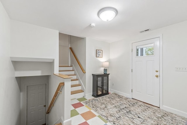 foyer entrance with tile patterned floors, baseboards, and stairway