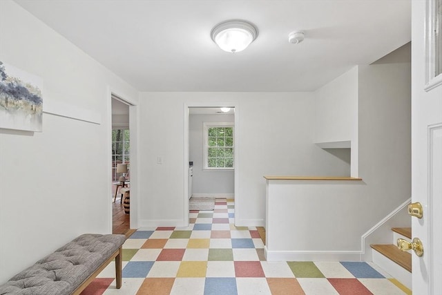 foyer entrance with baseboards, stairway, and light floors