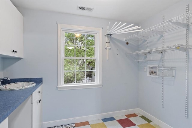 laundry area featuring a sink, light floors, and baseboards