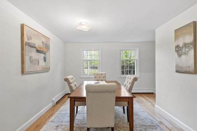 dining room featuring baseboard heating, light wood-style flooring, and baseboards