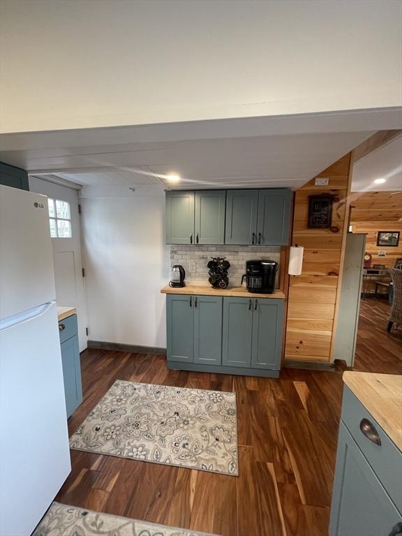 134 Kibbe Rd, Otis, MA 01029 - kitchen featuring wood walls, dark wood-type flooring, tasteful backsplash, and freestanding refrigerator