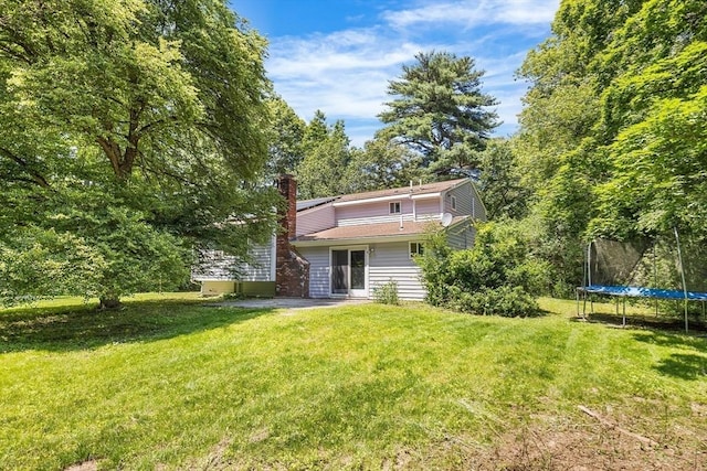 47 Churchill St, Sudbury, MA 01776 - rear view of property with a yard, a trampoline, and a chimney