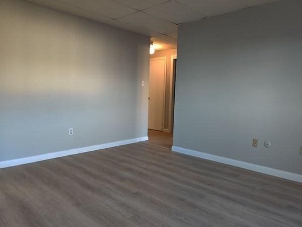 spare room featuring a drop ceiling and dark wood-type flooring