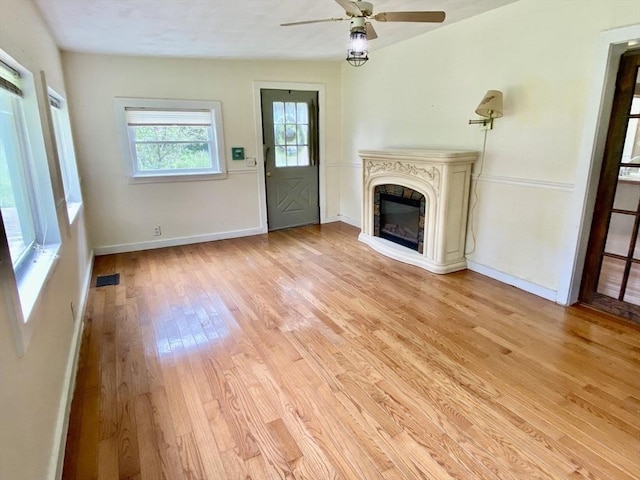 387 W Washington St, Hanson, MA 02341 - unfurnished living room featuring light wood-type flooring, a ceiling fan, and a glass covered fireplace