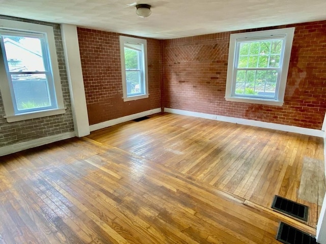 387 W Washington St, Hanson, MA 02341 - spare room featuring wood-type flooring, brick wall, and healthy amount of natural light
