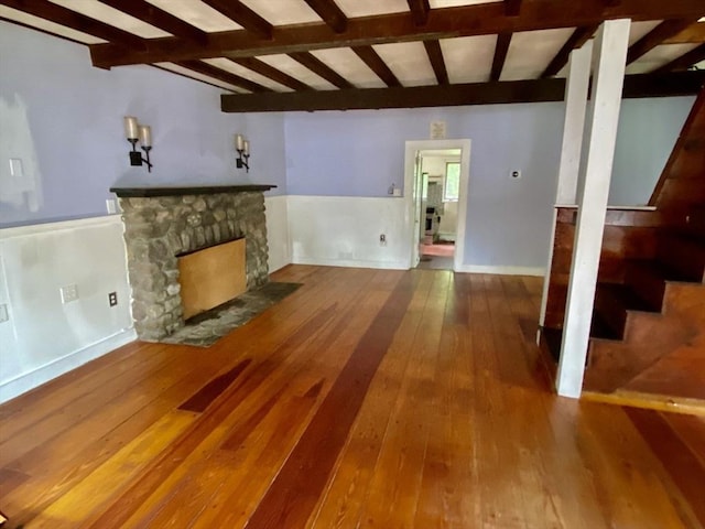 387 W Washington St, Hanson, MA 02341 - unfurnished living room featuring stairs, hardwood / wood-style floors, beamed ceiling, and a stone fireplace