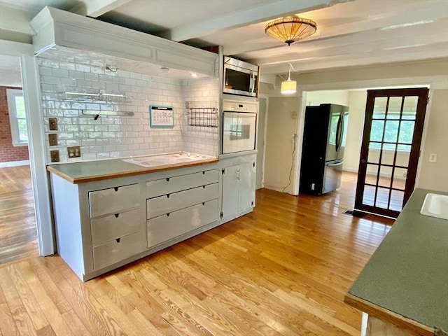 387 W Washington St, Hanson, MA 02341 - kitchen with oven, freestanding refrigerator, stainless steel microwave, light wood-type flooring, and beamed ceiling