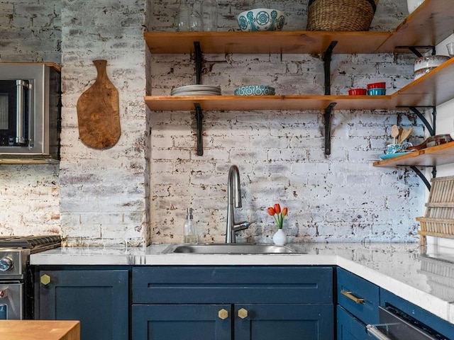 kitchen featuring open shelves, a sink, stainless steel gas range, blue cabinetry, and light countertops