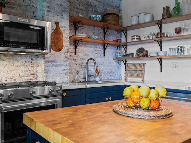 kitchen featuring appliances with stainless steel finishes, a sink, wood counters, and open shelves