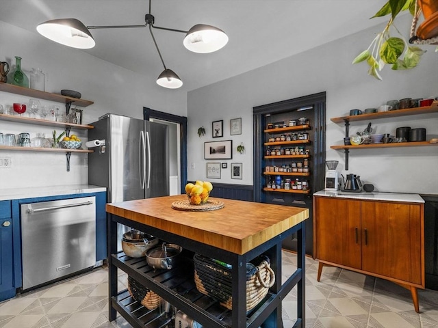 kitchen featuring open shelves, stainless steel dishwasher, light countertops, light flooring, and blue cabinets