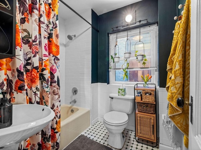 bathroom featuring toilet, shower / bath combination with curtain, and a sink