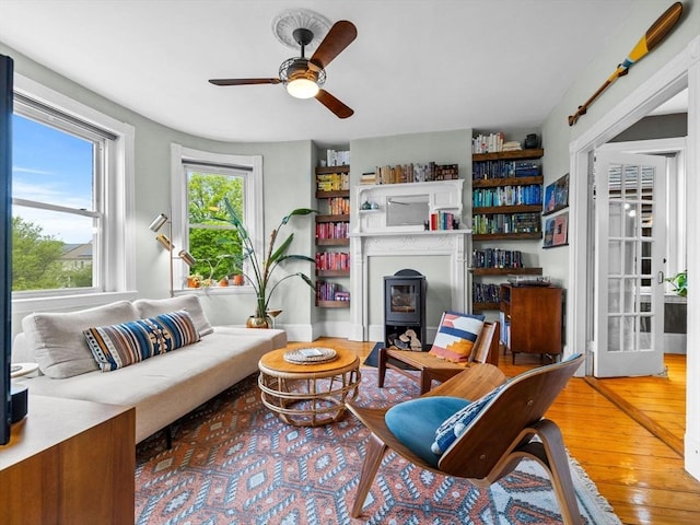 living room featuring a wood stove, a ceiling fan, and hardwood / wood-style flooring