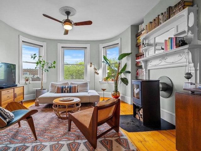 living area featuring healthy amount of natural light, ceiling fan, baseboards, and wood-type flooring