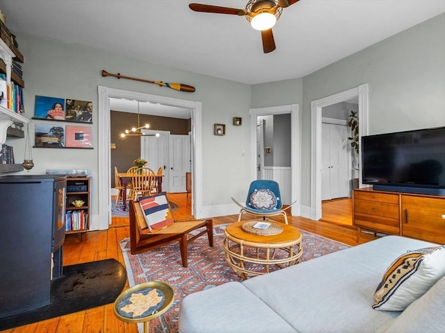 living area featuring wood finished floors, a ceiling fan, a chandelier, and baseboards