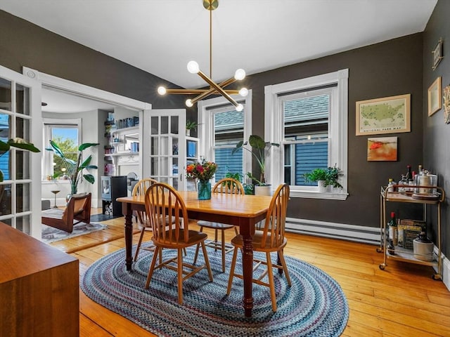 dining area featuring a baseboard radiator, light wood finished floors, and a chandelier