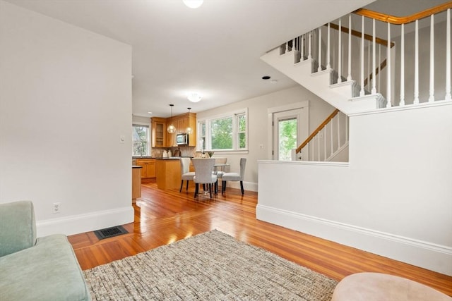 living area with baseboards, light wood-style floors, and stairs