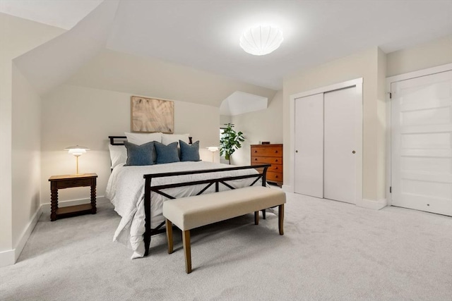 bedroom featuring light colored carpet, a closet, baseboards, and lofted ceiling
