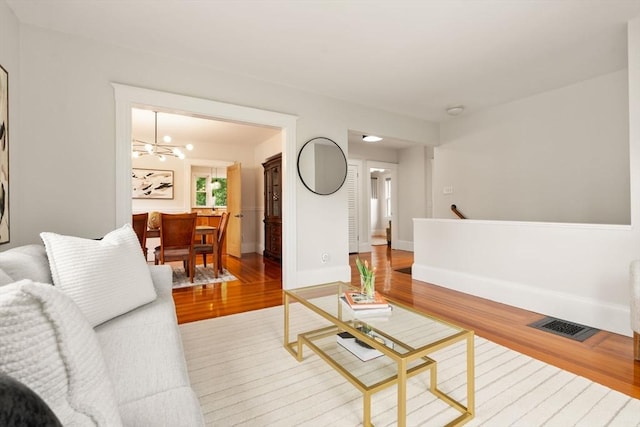 living room with wood finished floors, a chandelier, and baseboards