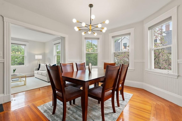 dining space with a chandelier, light wood finished floors, and baseboards