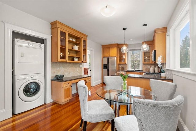 dining room with estacked washer and dryer, wood finished floors, baseboards, and recessed lighting